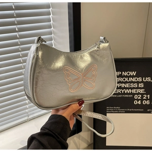 Detail der silbernen Metallic-Tasche mit rosa Schmetterlingsstickerei und plissierter Textur