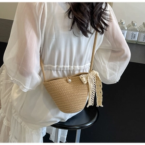 Detail of hand-woven straw bucket bag with pearl clasp and delicate white lace ribbon