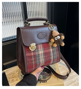 Detail of vintage brown PU leather handbag with British plaid fabric and plush monster charm