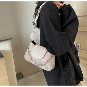 Detail der cremefarbenen Baguette-Tasche mit Jacquard-Muster, Metallkette und Riemen