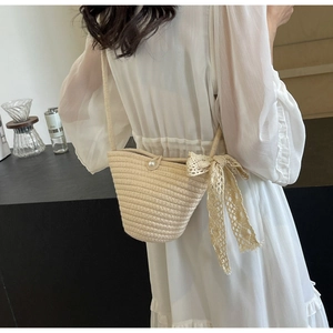 Close-up of woven bucket bag with elegant lace bow and decorative pearl button detail