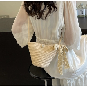 Detail of straw woven bag featuring elegant lace bow and decorative pearl button