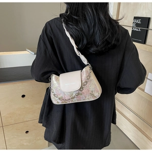 Détail du sac sous le bras en jacquard floral avec chaîne pétale dorée et rabat en cuir