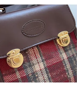 Detail of retro plaid tweed bag with brown leather flap and golden metal buckles
