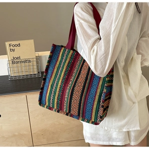 Detail of bohemian canvas tote bag showing colorful geometric patterns and red woven handles