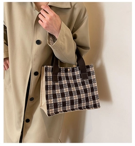 Detail of checkered canvas tote bag with brown handles and a secure magnetic metal snap