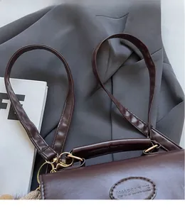 Close-up of dark brown faux leather shoulder bag with gold metal hardware and brand logo