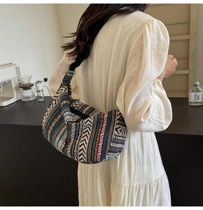 Détail d'un sac bandoulière tissé bohème avec motifs géométriques colorés et forme en croissant