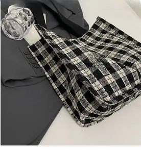 Close-up of black and white checkered woven tote bag placed on a grey blazer