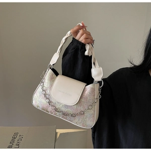 Détail d'un sac baguette français avec texture colorée et chaîne florale argentée