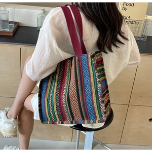 Detailed view of the ethnic woven tote bag with colorful geometric patterns on a model