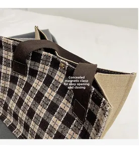 Detail of hidden magnetic closure on plaid canvas tote bag for secure and easy access