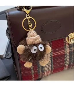 Close-up of a creative brown plush charm with knit hat on a stylish backpack