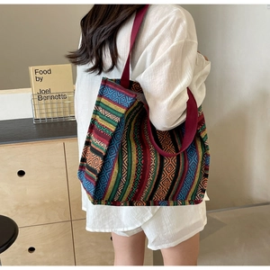 Bohemian canvas tote bag with colorful ethnic stripes worn by a model in a cozy room