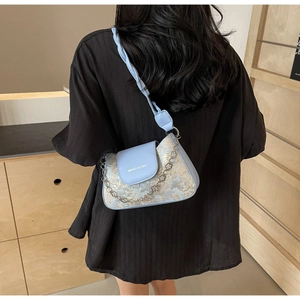 Détail du sac baguette bleu clair avec motif jacquard floral et chaîne en métal