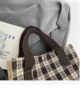 Close-up of brown checkerboard tweed fabric and reinforced canvas handle with gold stud