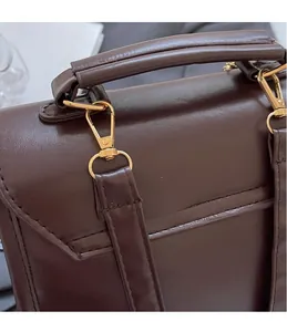 Close-up of golden metal hooks and textured handle on a vintage brown PU leather bag