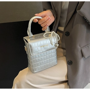 Detailed macro of silver faux crocodile leather handbag with pearl chain and heart pendant