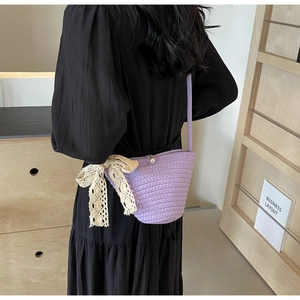 Detail of purple hand-knitted crossbody bag with lace bow and pearl button detail