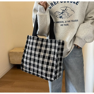 Detail of black and white houndstooth tote bag featuring durable wide webbing handles