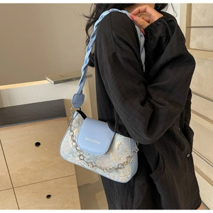 Détail du sac à bandoulière en jacquard bleu clair avec motif floral et chaîne fleurie en métal