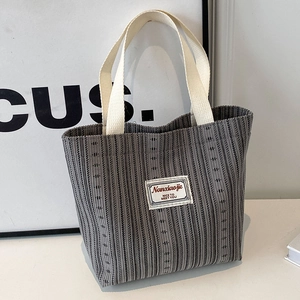 Vertical grey striped knit tote bag with thick cream straps and minimal patch detail