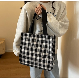 Detailed close-up of wide black woven handle on a black and white checkerboard tote bag