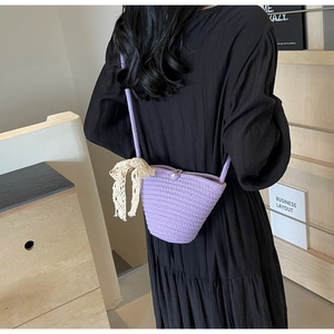 Detail of purple woven bucket bag featuring pearl buckle and elegant cream lace bow