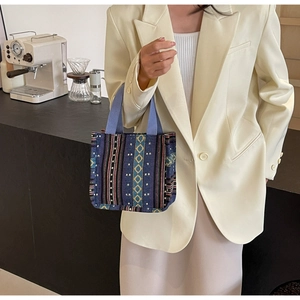 Close-up of geometric ethnic woven tote bag featuring deep blue canvas and colorful patterns