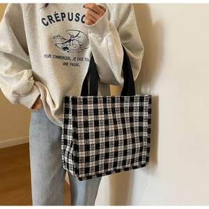 Close-up of black and white checkered canvas tote bag with reinforced handles