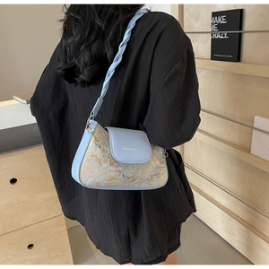 Détail du sac bandoulière jacquard bleu clair avec sangle tressée et chaîne dorée