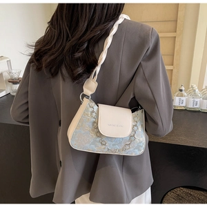 Detail aus floralem Jacquard-Stoff und Metallkette an einer modischen Baguette-Tasche