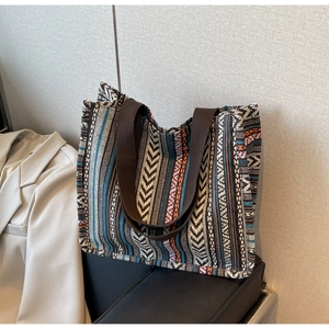 Close-up of ethnic style woven tote bag with geometric stripes on a leather bench