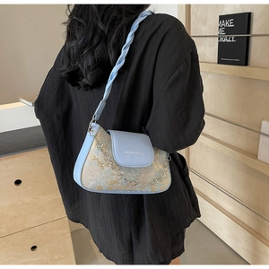 Détail du sac sous l'aisselle en cuir bleu avec motif floral et bandoulière tressée