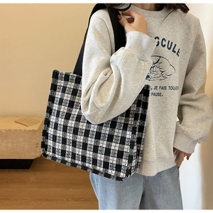 Close-up of black and white checkerboard tote bag with wide black fabric shoulder strap