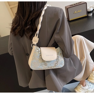 Détail de sac baguette vintage avec jacquard bleu et bandoulière en cuir tressé chic