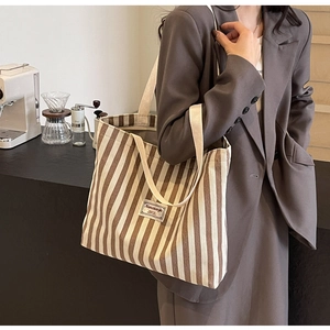 Detailansicht einer großen gestreiften Segeltuchtasche an einem Model im Café