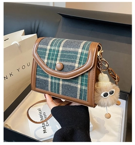 Detail of vintage plaid crossbody bag with brown leather trim and cute plush charm