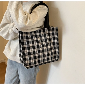 Detail view of the black and white checkerboard tote bag with woven texture and black handles