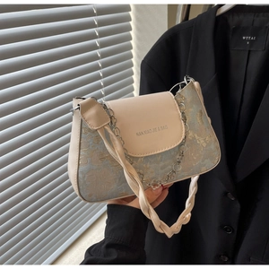 Gros plan du sac baguette en jacquard crème et bleu avec chaîne en métal doré