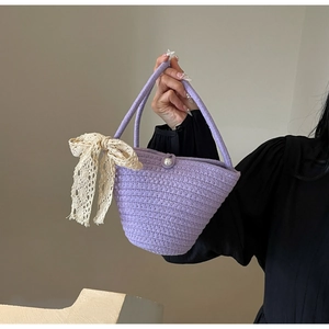 Detailed texture of purple woven bucket bag with pearl button and lace bow accent