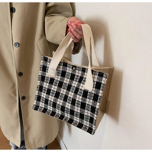 Close-up of black and white tweed checkered tote bag with cream canvas side and snap button