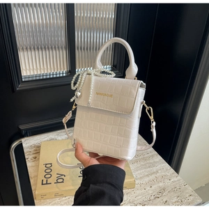 Detail of white crocodile pattern crossbody bag with pearl charm and heart pendant
