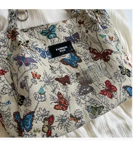 Detail of cream jacquard fabric with butterfly embroidery and a black fashion label