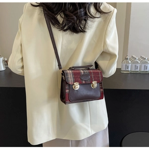 Close-up of vintage red plaid crossbody bag with brown leather and gold dual latches
