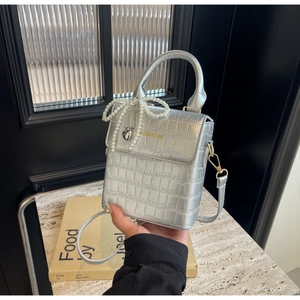 Detailed shot of silver crocodile pattern handbag with pearl bow and heart charm