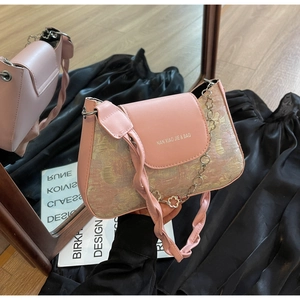 Détail du sac sous l'aisselle en jacquard rose avec bandoulière en cuir et chaîne à fleurs