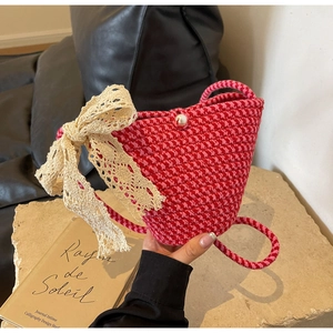 Detail of hand-woven crossbody bag with pink houndstooth pattern and lace bow decoration