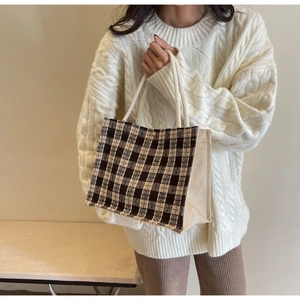 Detail of woven plaid tote bag with rope handle and magnetic metal clasp closure