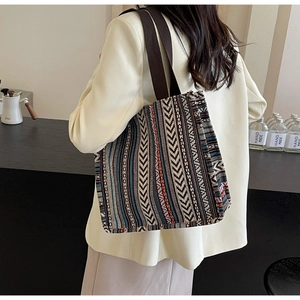 Detail of ethnic geometric woven tote bag with brown fabric straps shown in daily use